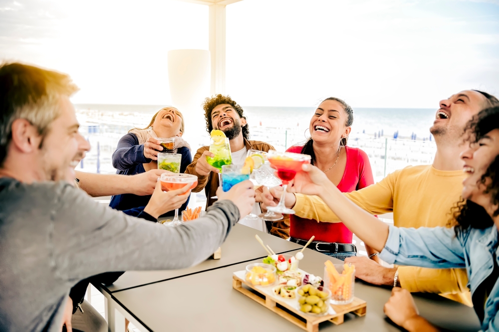 People laughing and sipping on happy hour drinks near the beach in the Myrtle Beach area
